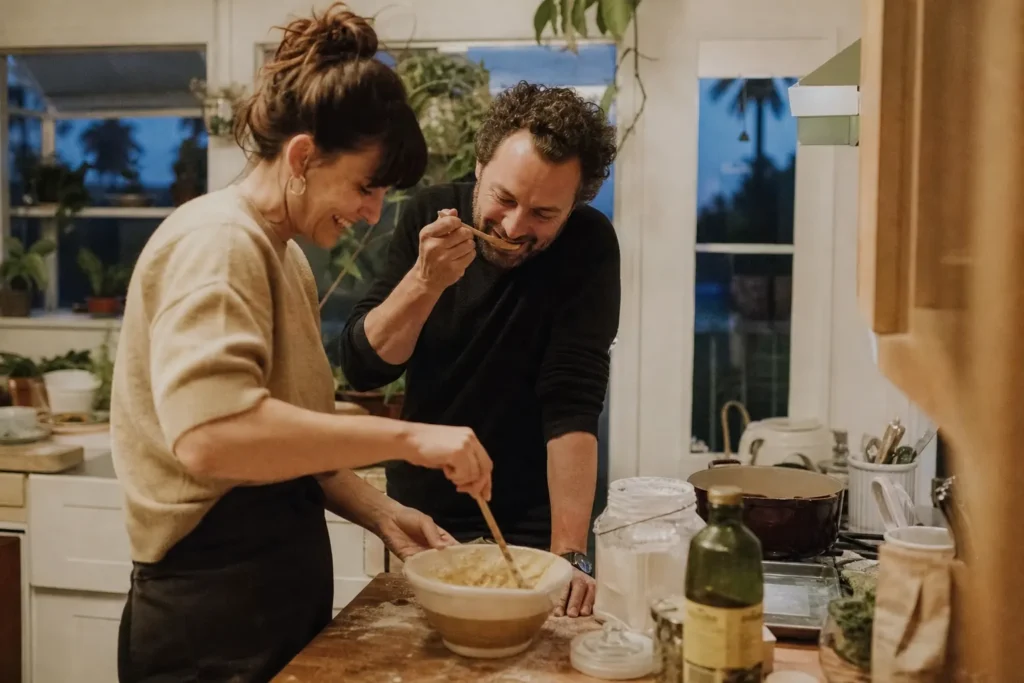 A couple laughing together while cooking a new recipe in a small home kitchen